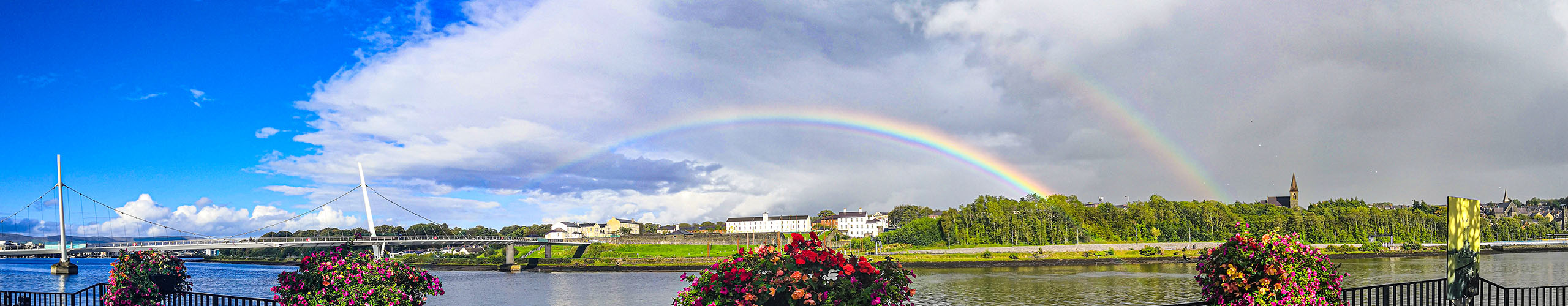 A picture of the Peace Bridge over the river foyle with a rainbow